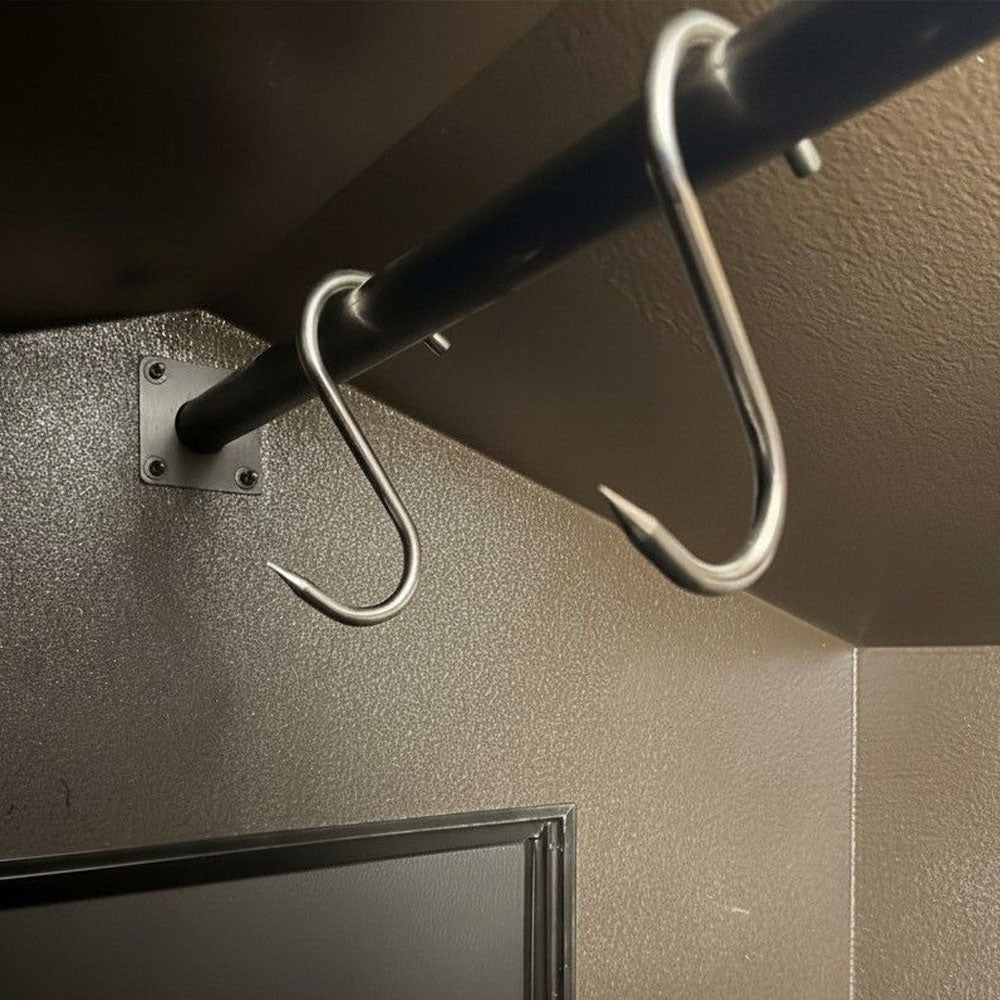 A close-up of a metal hanging rod with two silver S-hooks to hang deer within the air conditioned cooler