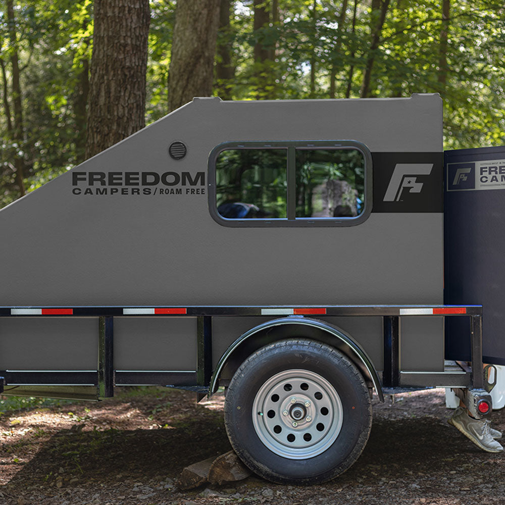 Freedom Camper on truck trailer in woods