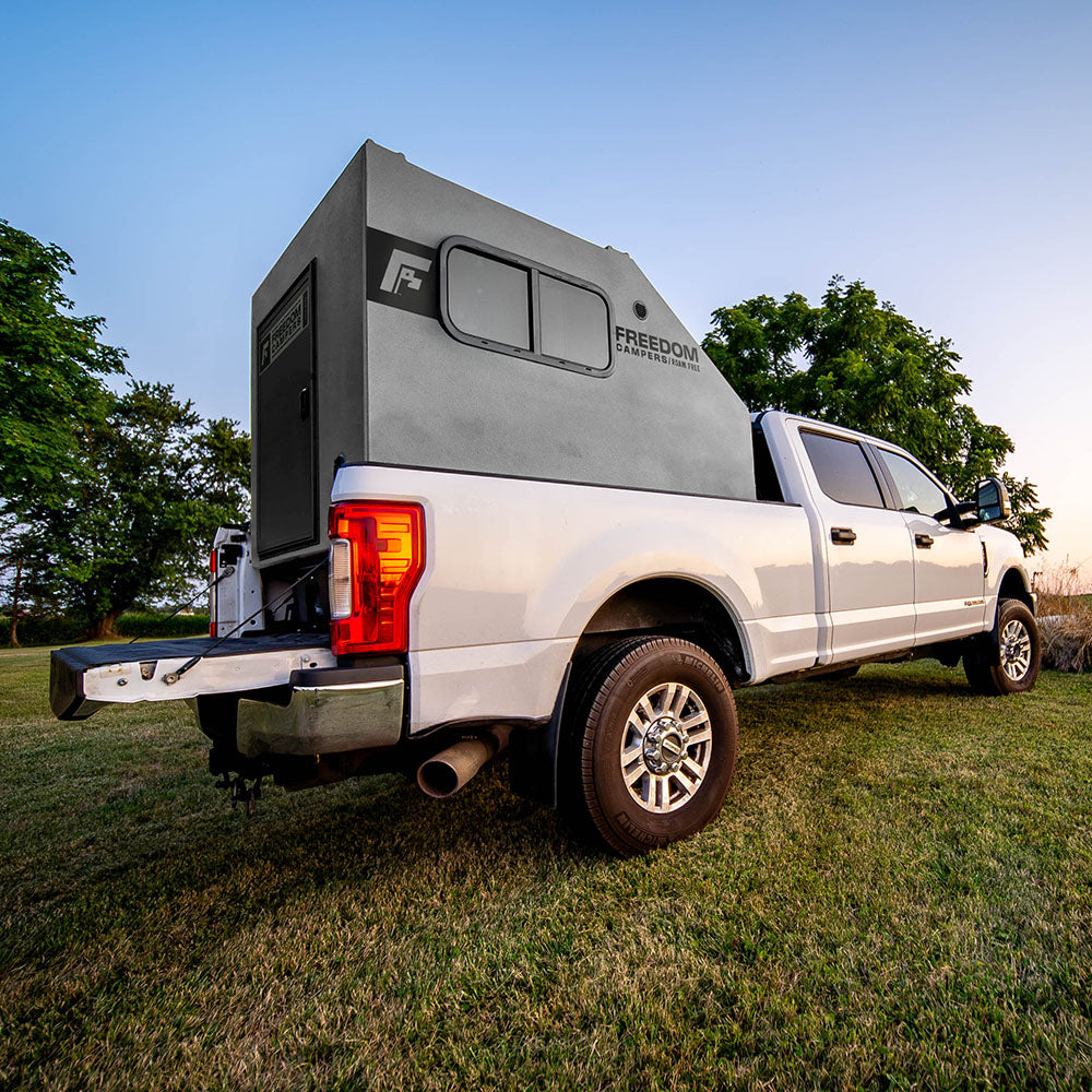 Gray Hunting Camper in the back of white truck