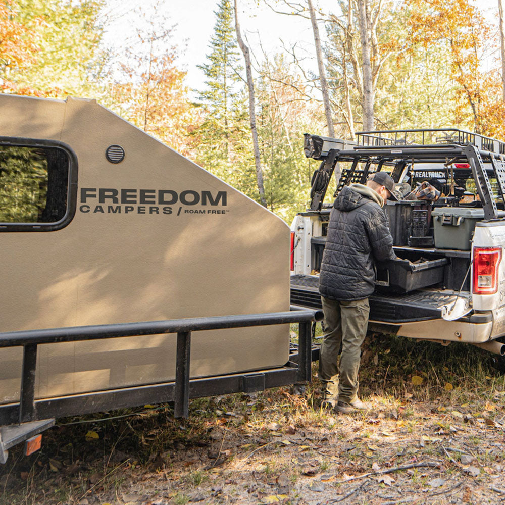 Hunter organizing supplies next to the hunter camper on a trailer